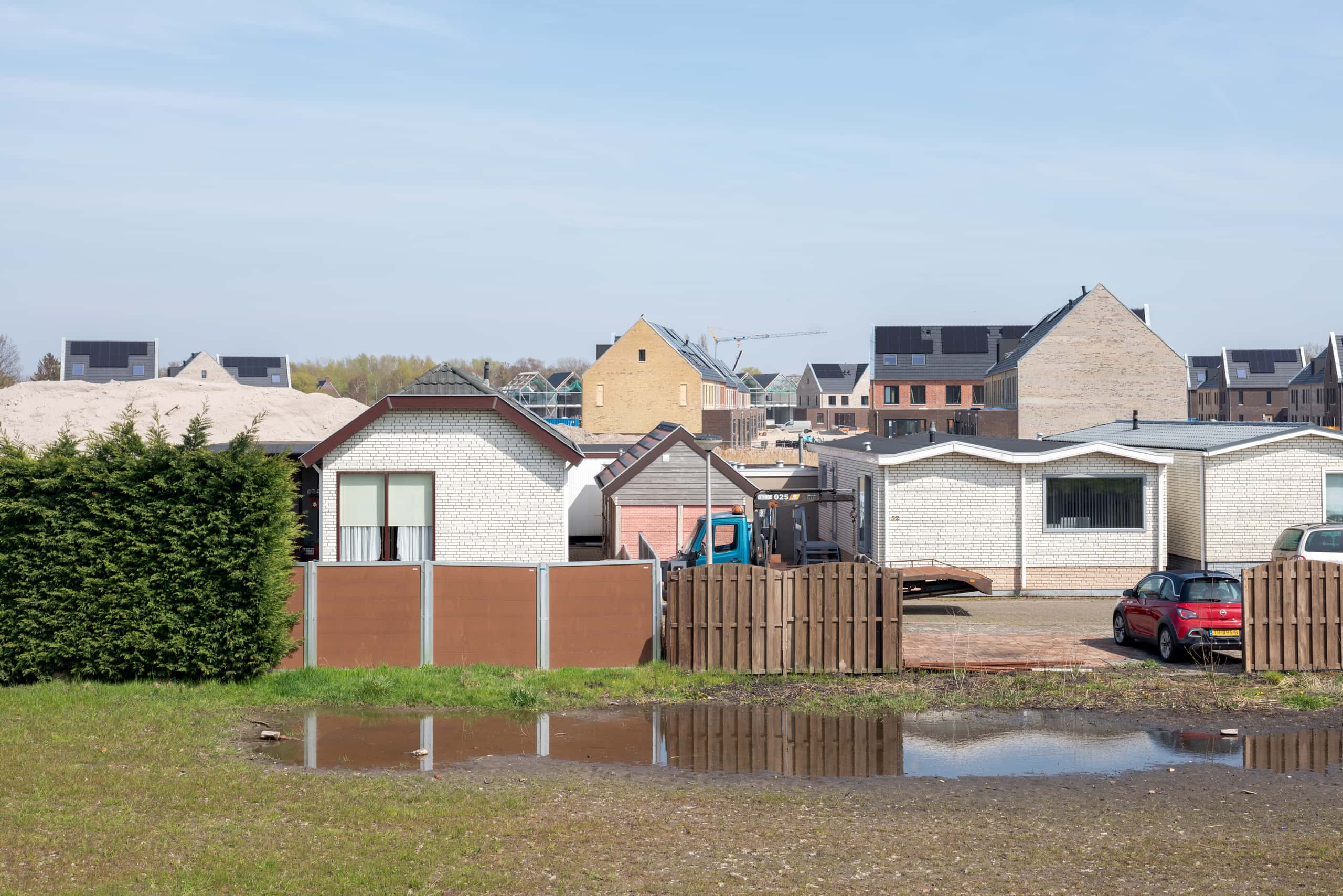 Een woonwijk met verschillende huizen, links een struik.