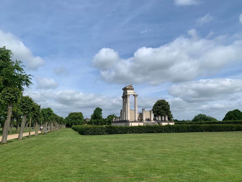 Een grasveld met een replica van Romeinse architectuur