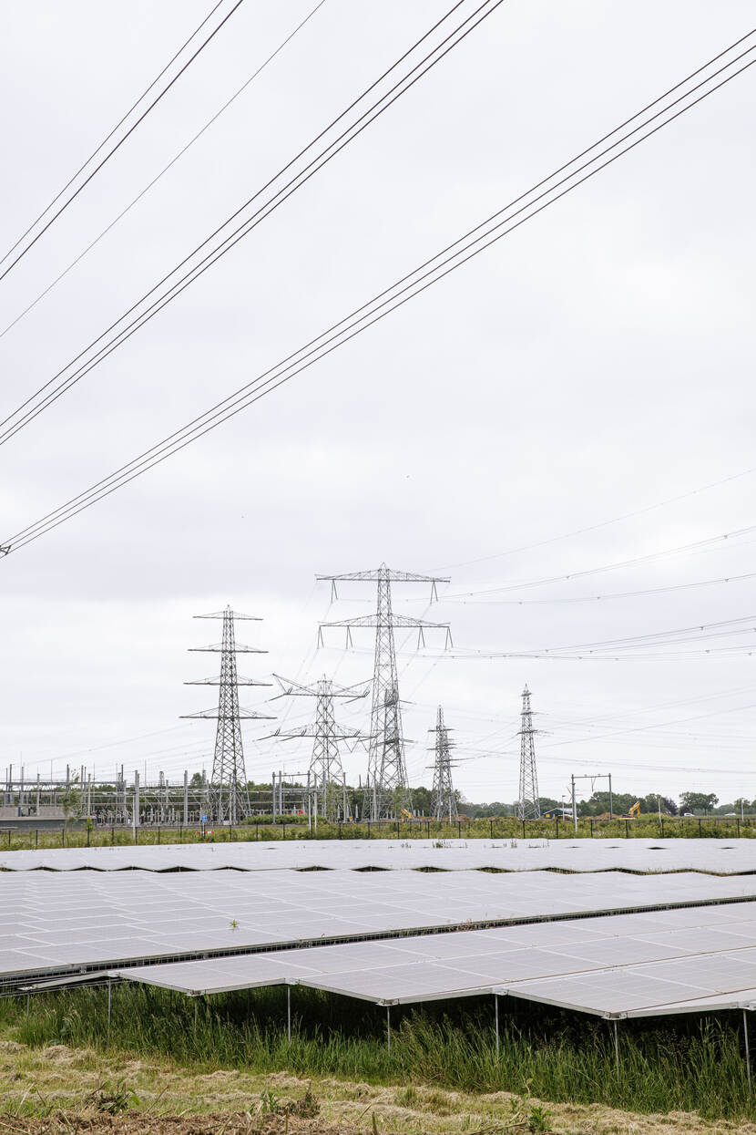 Zonnepanelen op de voorgrond, elektriciteitsmasten op de achtergrond