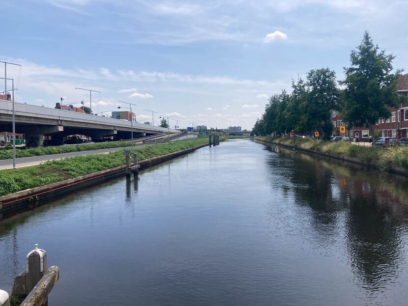Vaart langs parallelweg met huizen en snelweg
