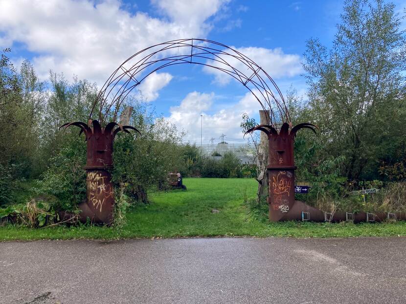 Een ronde metalen boog waar je onder door kunt lopen om op een grasveld uit te komen