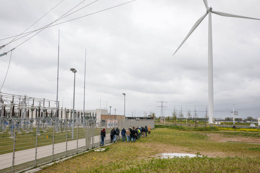 Deelnemers lopen langs een hek richting elektriciteitsmasten