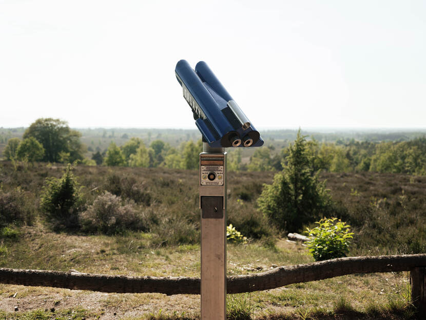 Verrekijker op een lange paal. Op de achtergrond heidelandschap